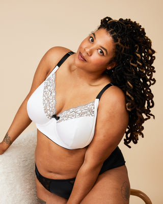 Woman wearing a white bra with lace details and black underwear on a beige background. This bra is the Willowdale Bra sewing pattern from Cashmerette.