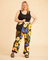 Woman wearing a black tank top and floral pants against a beige background. This is the Fiske Sleepwear Set sewing pattern from Cashmerette.