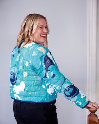 Woman wearing a blue quilted jacket with whale patterns against a plain background. This jacket is the Fairfax Quilted Jacket sewing pattern from "Sewing the Curve" by Jenny Rushmore.