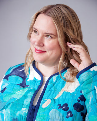 Woman wearing a colorful jacket with a neutral background. This jacket is the Fairfax Quilted Jacket sewing pattern from "Sewing the Curve" by Jenny Rushmore.