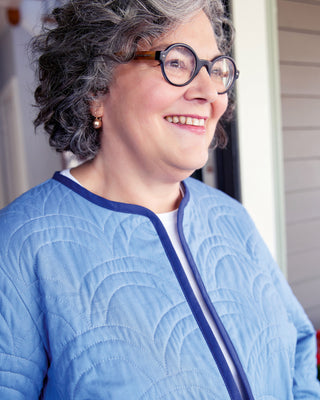 Person wearing a blue quilted jacket with a neutral background. This jacket is the Fairfax Quilted Jacket sewing pattern from "Sewing the Curve" by Jenny Rushmore.