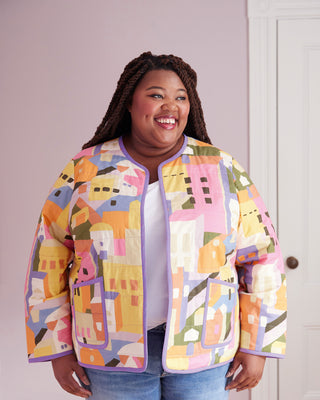 Person wearing a colorful geometric-patterned jacket against a plain background. This jacket is the Fairfax Quilted Jacket sewing pattern from "Sewing the Curve" by Jenny Rushmore.
