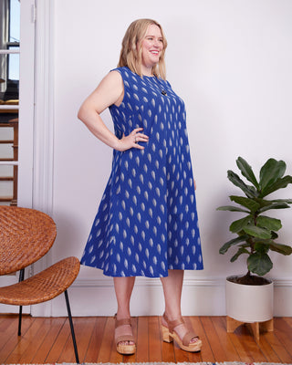 Woman wearing a blue dress with white patterns in a room with wooden floor and plant. This dress is the Montvale Dress & Tunic sewing pattern from "Sewing the Curve" by Jenny Rushmore.