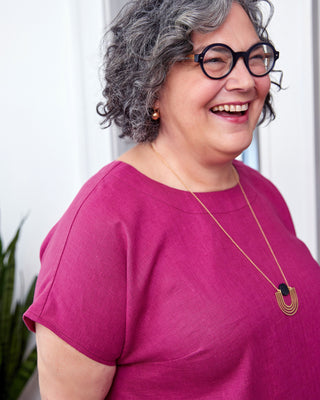 Person wearing a pink shirt and glasses, smiling. This top is the Montvale Dress & Tunic sewing pattern from "Sewing the Curve" by Jenny Rushmore.