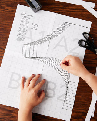Hands working with a pattern paper on a wooden table