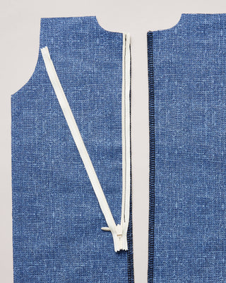 Blue denim fabric with a white zipper on a gray background