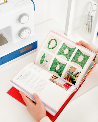 Open book with green geometric designs on a white surface. This book is Sewing the Curve by Jenny Rushmore.