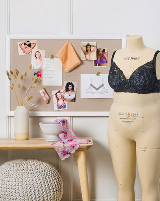 Mannequin wearing a black bra and beige pants with a bulletin board in the background.