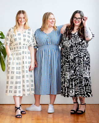 Three women wearing patterned dresses standing together indoors.  This dress is the Franconia Dress sewing pattern from Cashmerette.