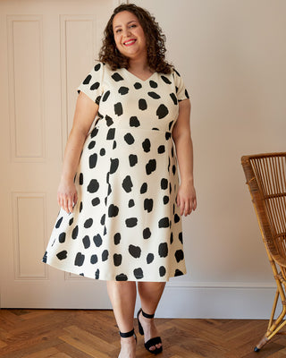 Woman wearing a black and white polka dot dress indoors. This dress is the Foxhill Dress sewing pattern from "Ahead of the Curve" by Jenny Rushmore.