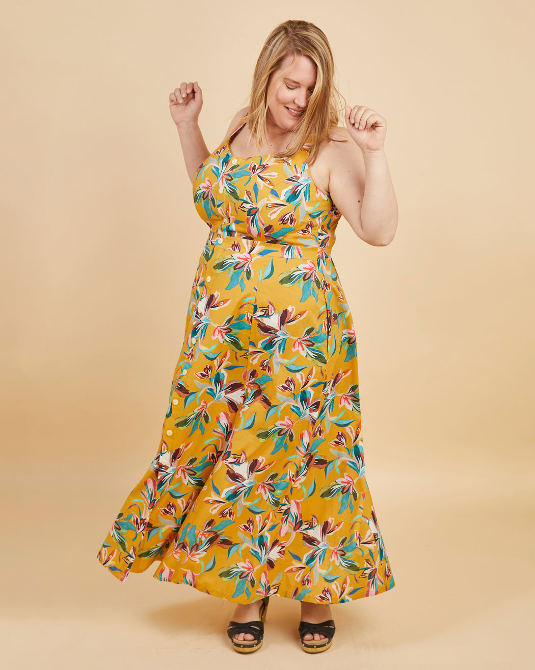 Woman wearing a yellow floral dress against a beige background. This is the Holyoke Maxi Dress & Skirt sewing pattern from Cashmerette.