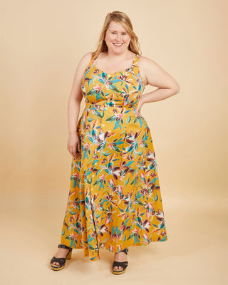Woman wearing a yellow floral dress on a beige background. This is the Holyoke Maxi Dress & Skirt sewing pattern from Cashmerette.