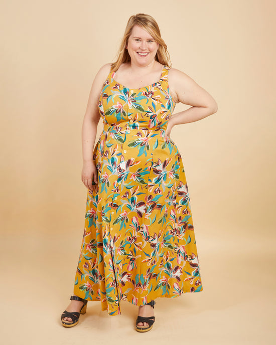 Woman wearing a yellow floral dress on a beige background. This is the Holyoke Maxi Dress & Skirt sewing pattern from Cashmerette.