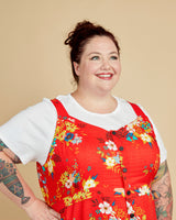 Woman wearing a red floral dress over a white shirt against a beige background. This is the Holyoke Maxi Dress & Skirt sewing pattern from Cashmerette.