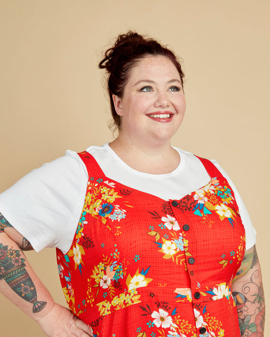 Woman wearing a red floral dress over a white shirt against a beige background. This is the Holyoke Maxi Dress & Skirt sewing pattern from Cashmerette.