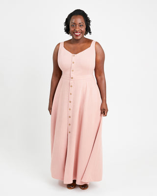 Woman wearing a pink sleeveless dress with buttons on a white background. This is the Holyoke Maxi Dress & Skirt sewing pattern from Cashmerette.