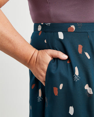 Person wearing a dark green skirt with abstract pattern, holding their hand in their pocket.. This is the Holyoke Maxi Dress & Skirt sewing pattern from Cashmerette.
