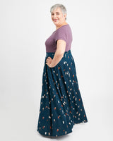Woman wearing a purple top and blue skirt with a pattern on a white background. This is the Holyoke Maxi Dress & Skirt sewing pattern from Cashmerette.