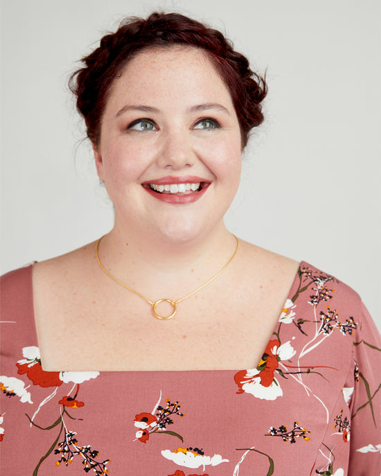 Woman wearing a floral dress with a plain background. This dress is the Upton Dress & Skirt sewing pattern from Cashmerette.
