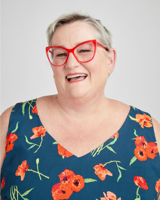 Person wearing a blue floral dress with red glasses on a white background. This dress is the Upton Dress & Skirt sewing pattern from Cashmerette.