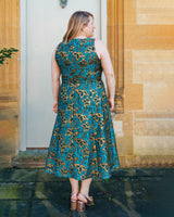 Woman wearing a blue and gold patterned dress standing in front of a stone building.. This dress is the Upton Dress & Skirt sewing pattern from Cashmerette.