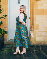 Woman in a teal patterned dress standing in front of a door.. This dress is the Upton Dress & Skirt sewing pattern from Cashmerette.