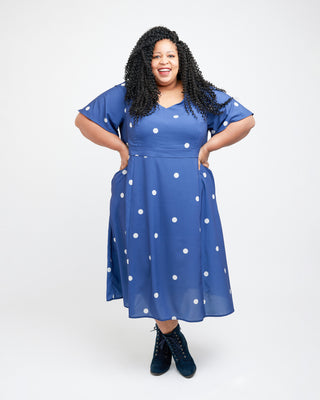 Woman wearing a blue dress with white polka dots on a white background. This dress is the Upton Dress & Skirt sewing pattern from Cashmerette.