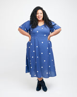 Woman wearing a blue dress with white polka dots on a white background. This dress is the Upton Dress & Skirt sewing pattern from Cashmerette.