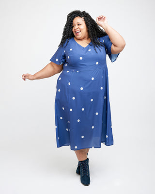 Woman wearing a blue dress with white polka dots on a white background. This dress is the Upton Dress & Skirt sewing pattern from Cashmerette.