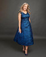 Woman wearing a blue dress against a gray background. This dress is the Upton Dress & Skirt sewing pattern from Cashmerette.