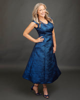 Woman wearing a blue dress against a gray background. This dress is the Upton Dress & Skirt sewing pattern from Cashmerette.