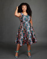 Woman wearing a floral dress against a gray background. This dress is the Upton Dress & Skirt sewing pattern from Cashmerette.