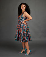 Woman wearing a floral dress against a gray background. This dress is the Upton Dress & Skirt sewing pattern from Cashmerette.