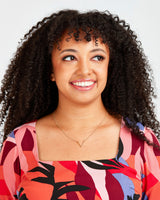 Woman with curly hair wearing a colorful patterned top against a plain background. This dress is the Upton Dress & Skirt sewing pattern from Cashmerette.