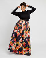 Woman wearing a black long-sleeve top and floral skirt on a white background. This dress is the Upton Dress & Skirt sewing pattern from Cashmerette.