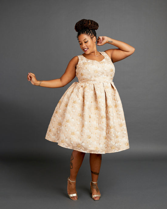 Woman wearing a beige floral dress against a gray background. This dress is the Upton Dress & Skirt sewing pattern from Cashmerette.