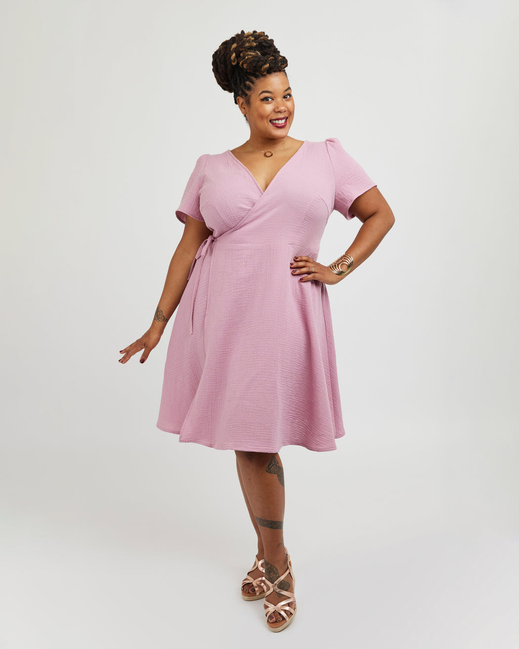 Woman wearing a pink dress against a white backgroundThis dress is the Roseclair Wrap Dress sewing pattern from Cashmerette.