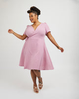 Woman wearing a pink dress on a white background. This dress is the Roseclair Wrap Dress sewing pattern from Cashmerette.