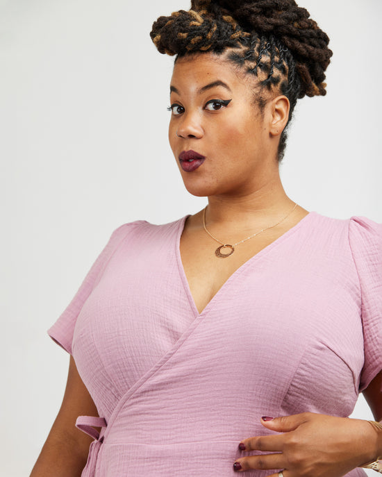 Woman wearing a pink dress against a white background. This dress is the Roseclair Wrap Dress sewing pattern from Cashmerette.