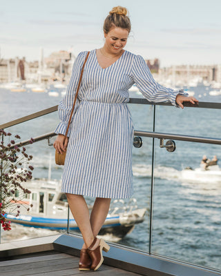 Woman in a striped dress standing on a balcony overlooking water with boats. This dress is the Kineton Dress & Top sewing pattern from Cashmerette.