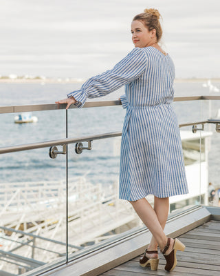 Woman in a blue and white striped dress standing on a balcony with a waterfront view. This dress is the Kineton Dress & Top sewing pattern from Cashmerette.