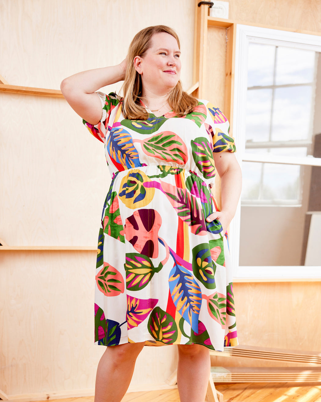 Woman wearing a colorful dress with leaf pattern indoors. This dress is the Kineton Dress & Top sewing pattern from Cashmerette.