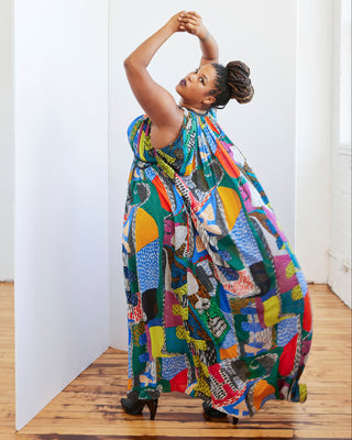 Woman wearing a colorful patterned dress in a minimal indoor setting. This dress is the Rockwell Dress sewing pattern from Cashmerette.