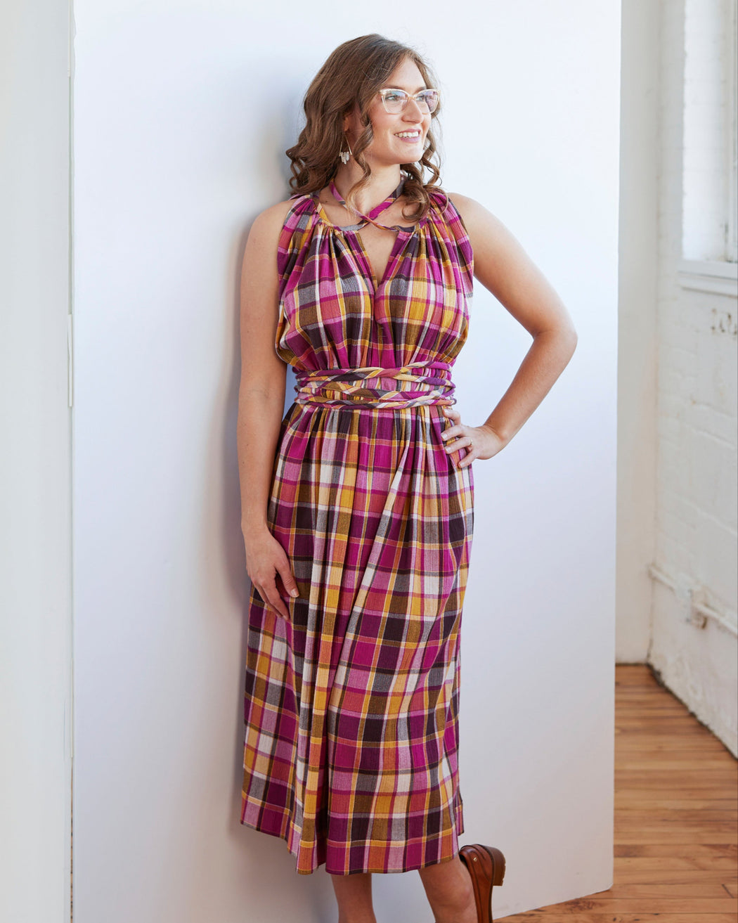 Woman wearing a plaid dress standing against a white wall. This dress is the Rockwell Dress sewing pattern from Cashmerette.