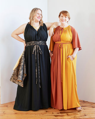 Two women wearing long dresses standing against a white wall. This dress is the Rockwell Dress sewing pattern from Cashmerette.