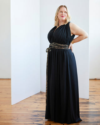 Woman wearing a black dress with a belt in a room with wooden flooring. This dress is the Rockwell Dress sewing pattern from Cashmerette.