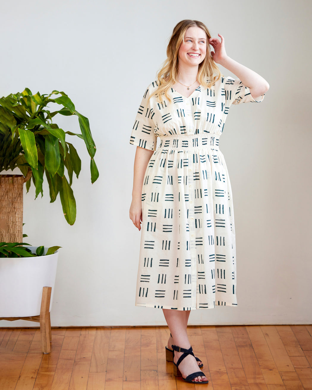 Woman wearing a patterned dress standing indoors with a plant in the background. This dress is the Franconia Dress sewing pattern from Cashmerette.