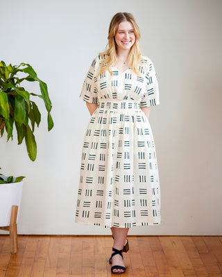 Woman wearing a patterned dress standing indoors with a plant in the background. This dress is the Franconia Dress sewing pattern from Cashmerette.