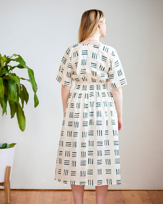 Woman wearing a patterned dress standing in a room with a plant and wooden floor. This dress is the Franconia Dress sewing pattern from Cashmerette.