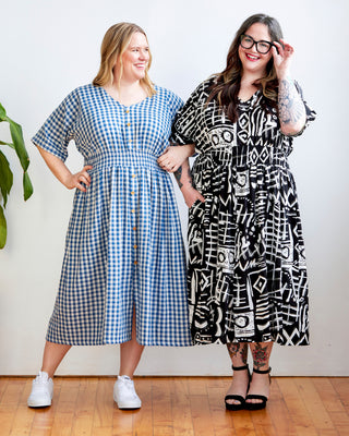 Two women wearing patterned dresses standing indoors with a white wall background. This dress is the Franconia Dress sewing pattern from Cashmerette.